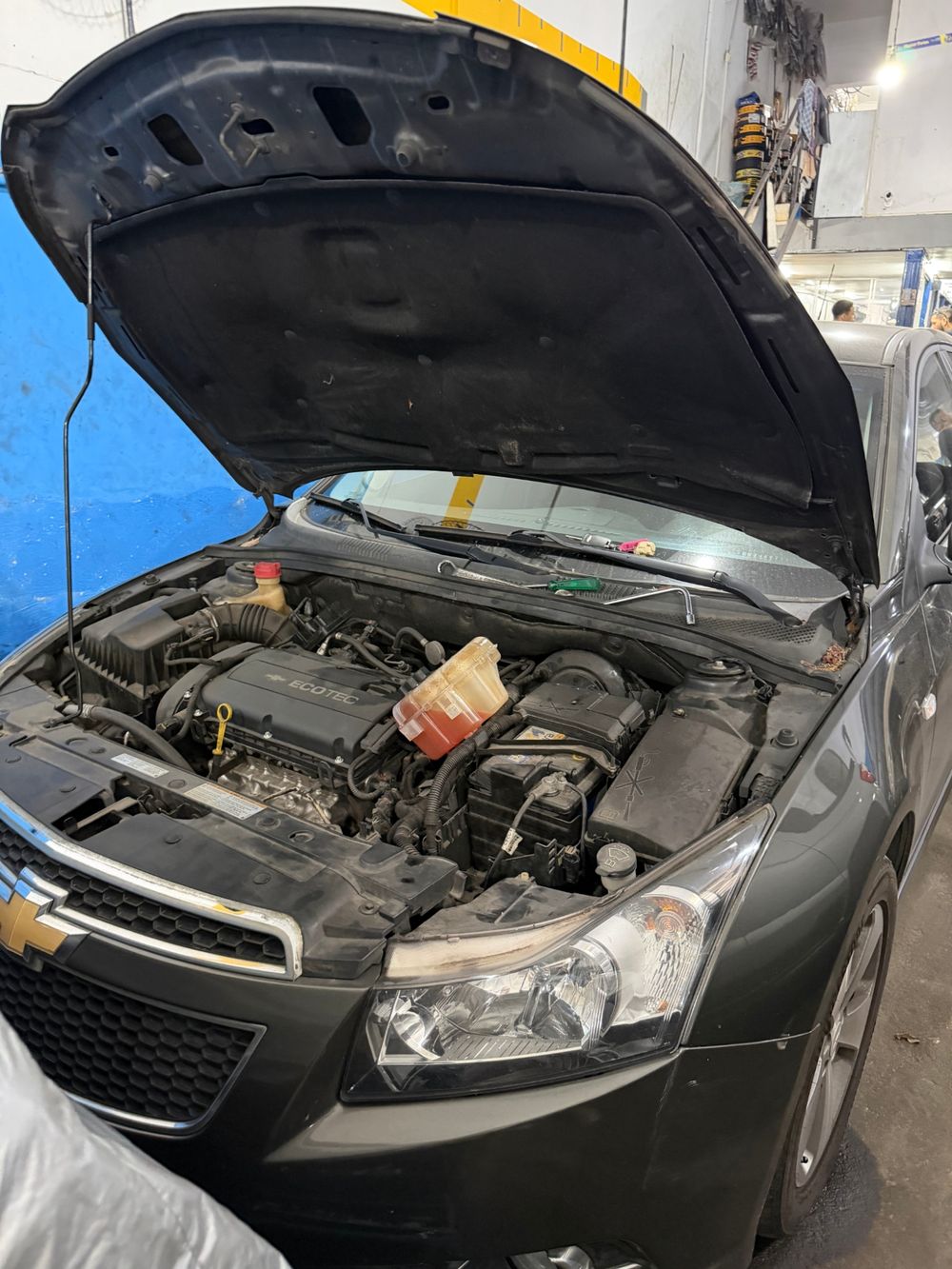 Sedã com o capô aberto, mostrando o compartimento do motor