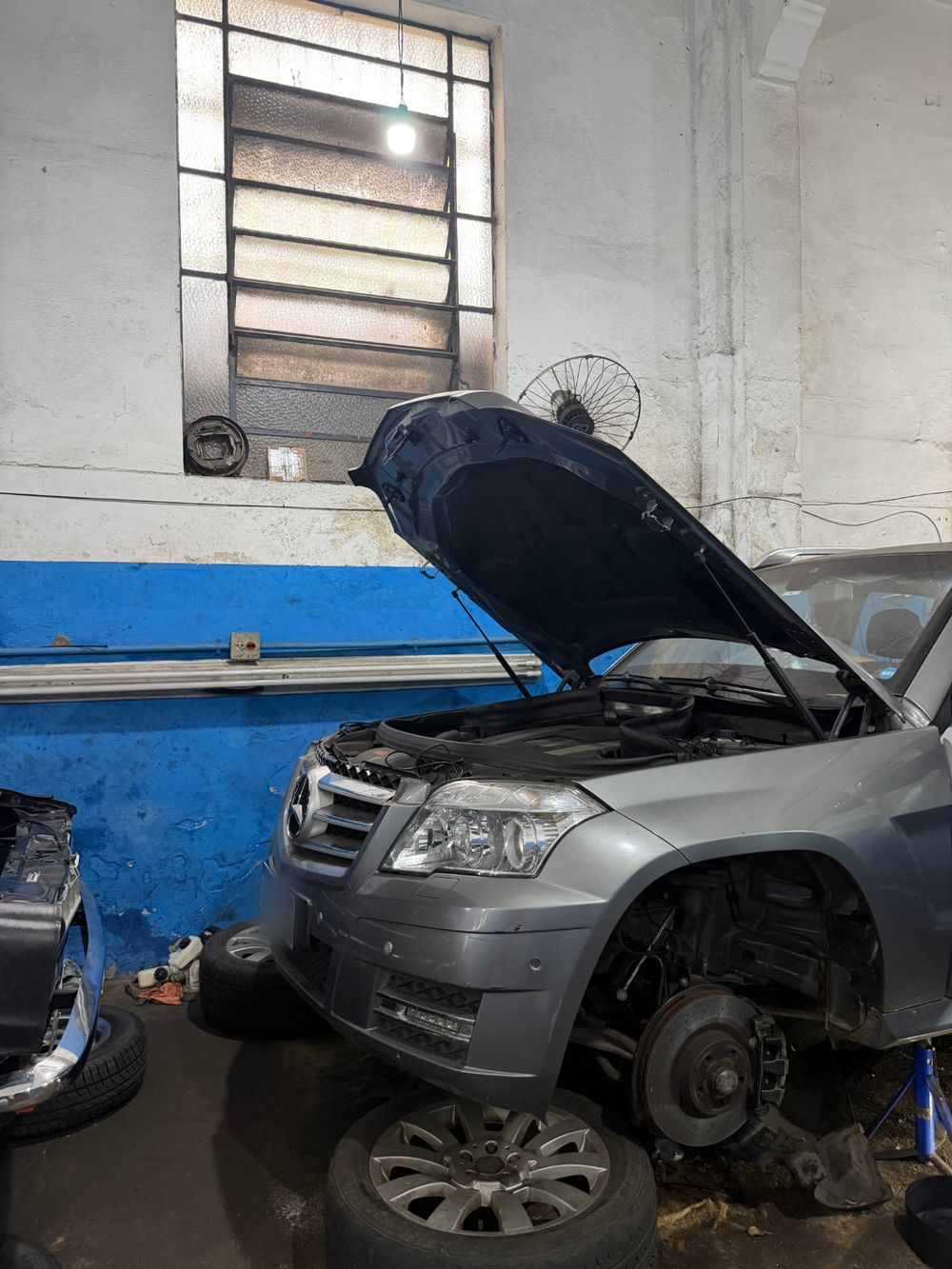 SUV cinza com o capô aberto em manutenção